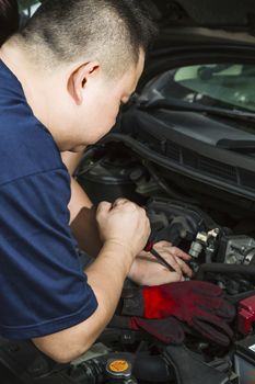 An Asian car mechanic fixing a car. 