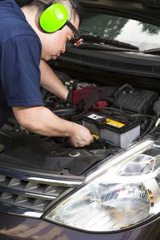 A car mechanic inspecting the car battery. 