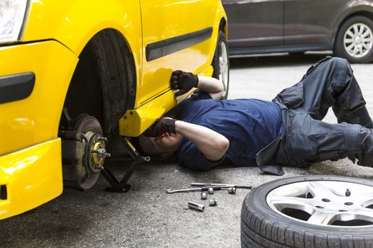 A mechanic underneath a car checking the car condition