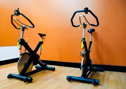 Two black with yellow bike machines in the gym