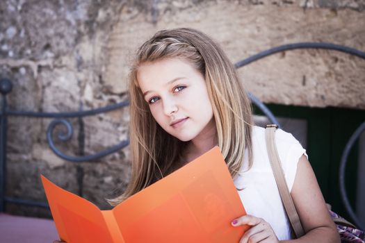 A teenager reading from a file, looking at camera, positive feeling, candid shot