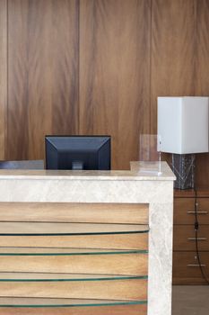 A close up of a hotel lobby with a computer monitor behind the counter