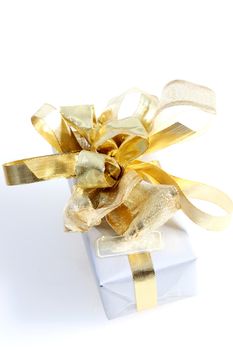 Decorative gift with an ornate gold bow composed of several different types of ribbon against a white background, high angle view