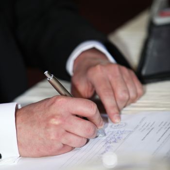 Closeup of the hands of a business man completeing a questionnaire with a ballpoint pen