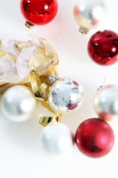 Overhead view on white of scattered red and white Christmas baubles with a decorative gold ribbon
