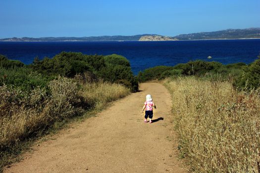 Little girl (one year and seven months of age) makes first steps on the  Sardinia ground
