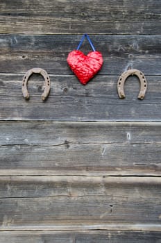 two rusty horseshoe and red heart symbol on old farm wooden wall