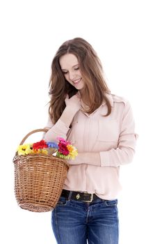 Smiling young teenage girl with a wicker basket of fresh flowers on her arm looking down at them with a smile, isolated on white