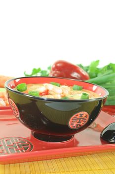 Curry soup with shrimp, red pepper and coconut milk on bright background