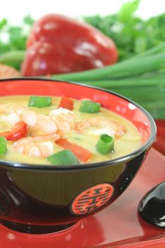 Curry soup with shrimp, red pepper, chili and coconut milk on light background