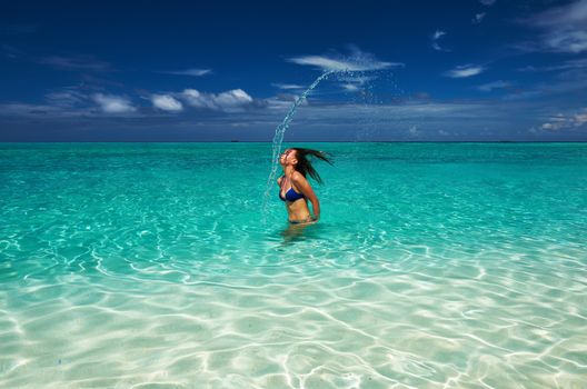 Woman splashing water with her hair in the ocean