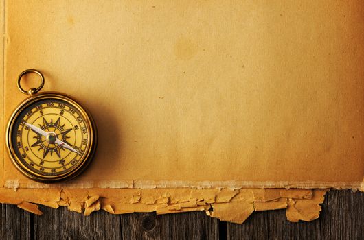 Antique brass compass over old paper background