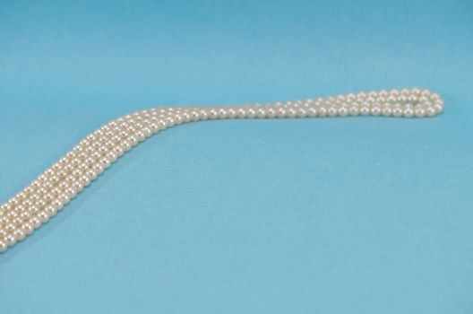 pearl necklace collar turn curve closeup on blue background.