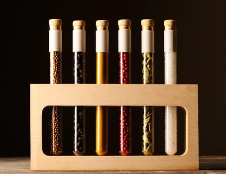Spices in beakers on wooden table against dark background