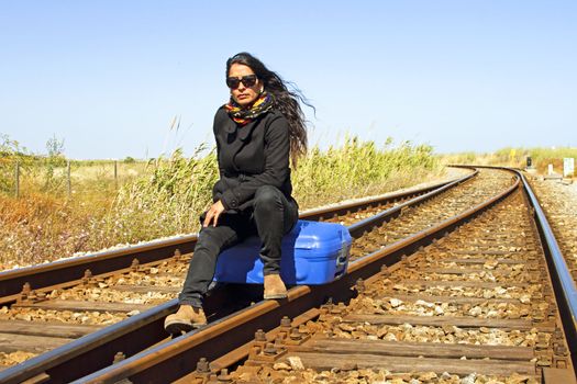 Young woman with her suitcase on a railroad track