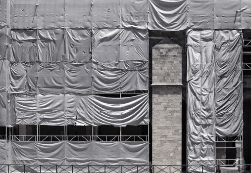 Building under conctruction covered with wrinkled tarpaulin canvas