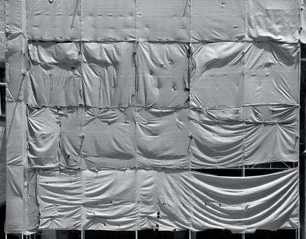 Building under conctruction covered with wrinkled tarpaulin canvas