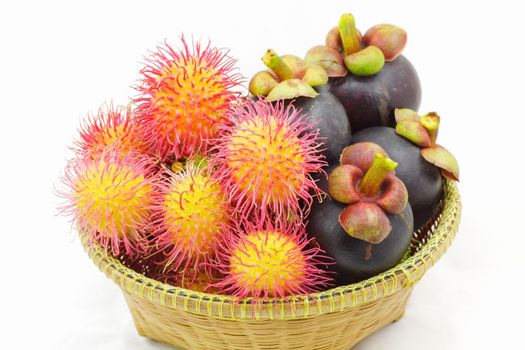 Fresh organic rambutan and mangosteen Thai fruits in wicker basket.