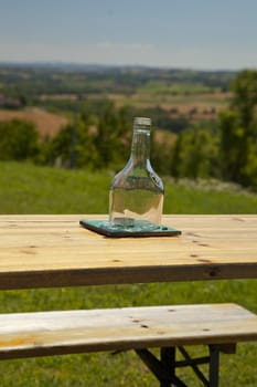Wooden table with candle covered by glass over beautiful landscape