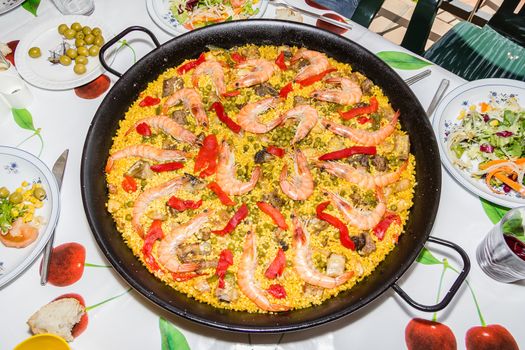 Traditional spanish paella cooked in a pan, with yellow rice and seafood