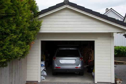 A small garage filled with clutter anda large car