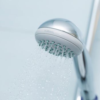 Silver shower with flowing waterin the bathroom