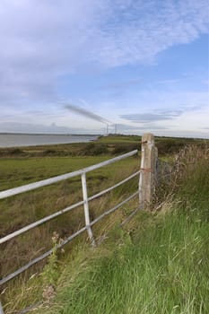 gate to a field with the chimney stacks of a power plant in Ireland in the background