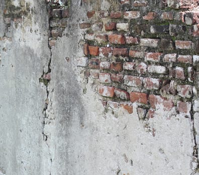 A section of an old and crumbling wall with underlying aged bricks exposed