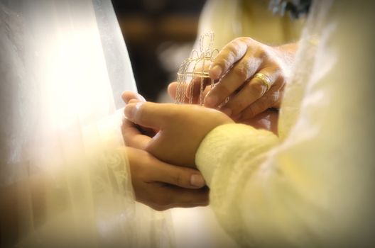 Closeup of hand of priest handing over to groom the wedding Arras with 13 coins symbolizing the groom's promise to his bride to support her and their family