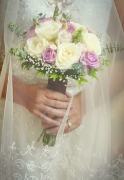 Close-up of wedding bouquet made of white and pink roses and held by bride during a wedding ceremony.