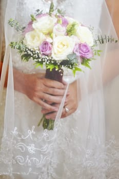 Close-up of wedding bouquet made of white and pink roses held by bride during a wedding ceremony.