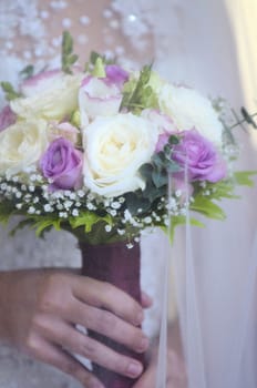 Close-up of wedding bouquet made of white and pink roses held by bride during a wedding ceremony.