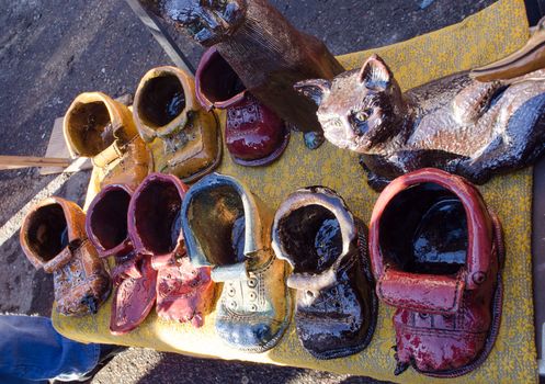 adorable cute rural crafts clay ceramic boots shoes and cat figures sold in outdoor street fair market.