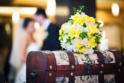 Wedding bouquet with bride and groom blured in background 