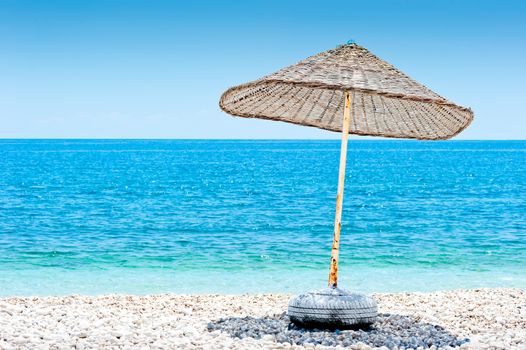 lone wicker umbrella on the beach