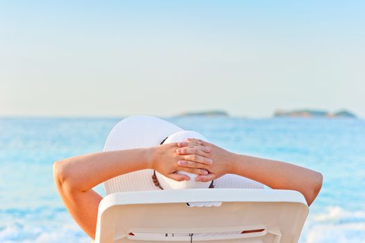 woman sunbathing on a lounger on the beach wearing a hat