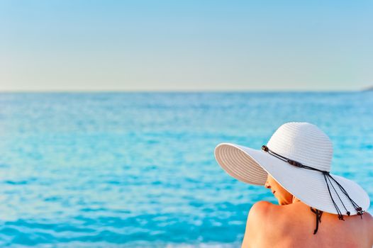 girl in white hat on the beach sunbathing