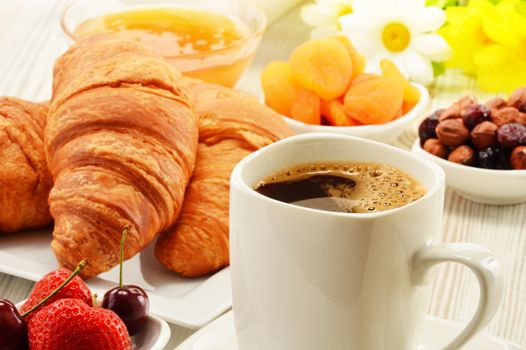 Breakfast with croissants, cup of coffee and fruits