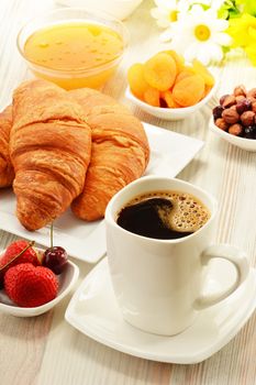 Breakfast with croissants, cup of coffee and fruits