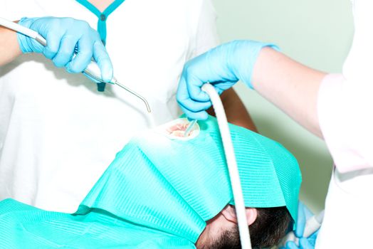 Dentist cleaning teeth to men patient