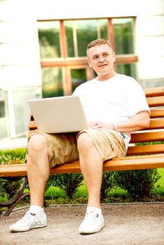 Portrait of a man with laptop sitting on bench