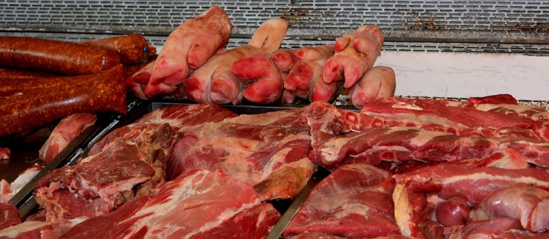 Pig's feet, sausages and various cuts of meat and offal on display at a butcher shop