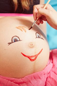 Drawing faces on the belly of pregnant woman