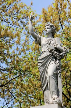 A stone statue of a barefoot woman pointing upward and holding a large crucifix and floral wreath, on a tomb at Graceland Cemetery, Chicago, Illinois, USA