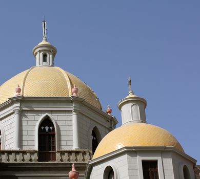 Two yellow cupolas against a blue sky at Immaculate Conception Cathedral in Mazatlan, Mexico