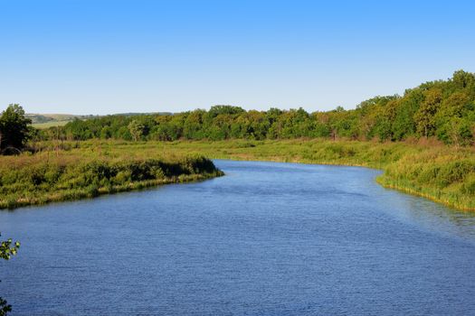 small lake with blue water surrounded by green forest