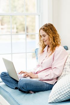 Caucasian woman using laptop computer sitting on couch at home