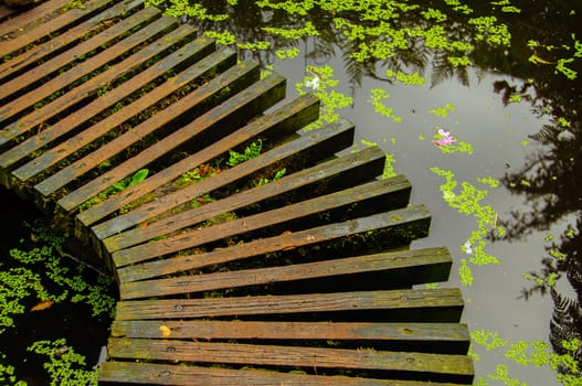 A brown wooden bridge in a japanese garden