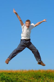 Happy and winning boy jumping on the blue sky background