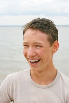 young teenager laughing on the beach in summertime